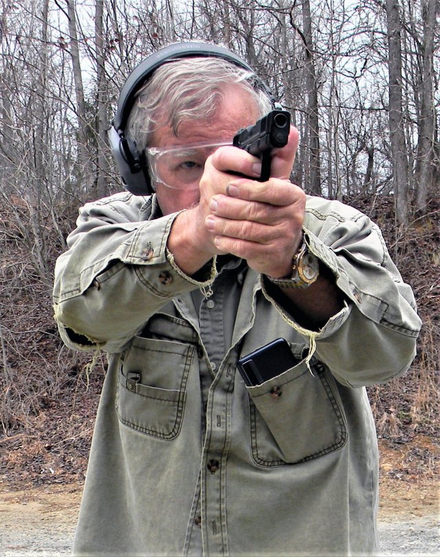 Bob Campbell wearing ear muffs and shooting the Smith and Wesson SCX with a two-handed grip