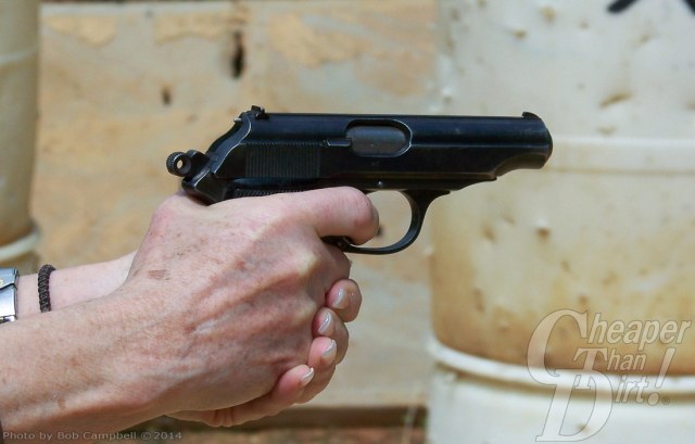 Hand holding an original black Walther PP pointed to the right