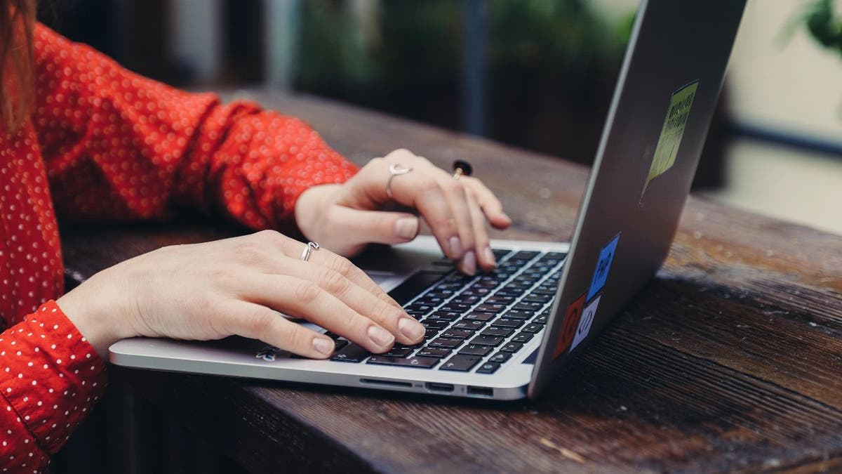 A woman types on a laptop.