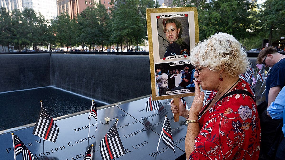 Olga Colon blows a kiss at the south reflecting pool during the 9/11 commemoration ceremony at the National 9/11 Memorial and Museum.