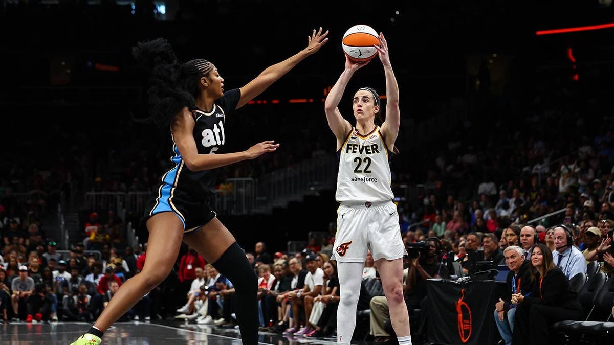 Caitlin Clark shoots the basketball while Angel Reese defends
