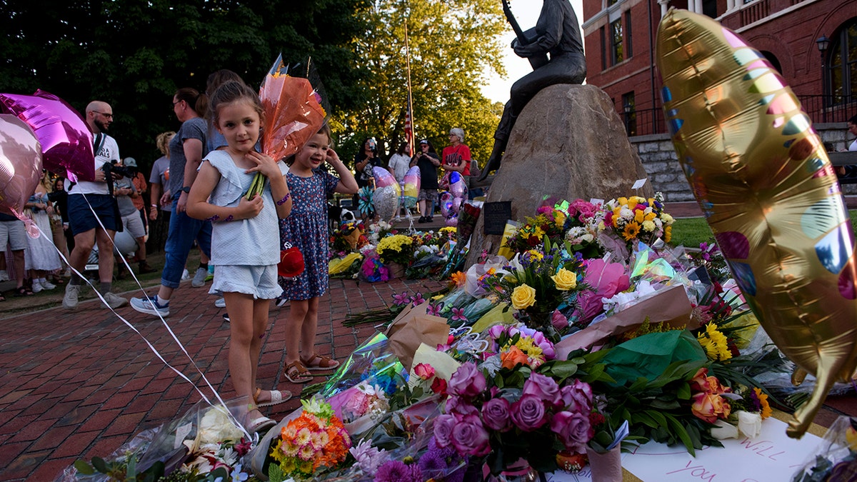 Girl holds flowers in front of tribute for Dolly Parton