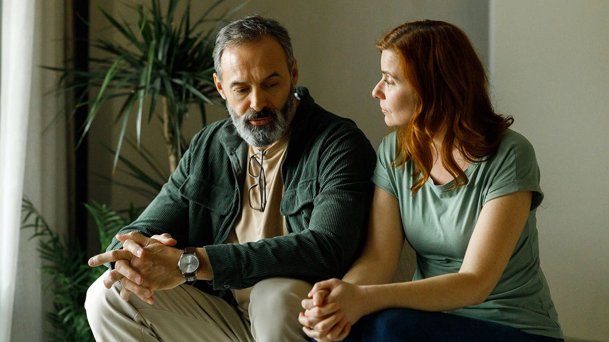Mature couple arguing while seated on a sofa at home.