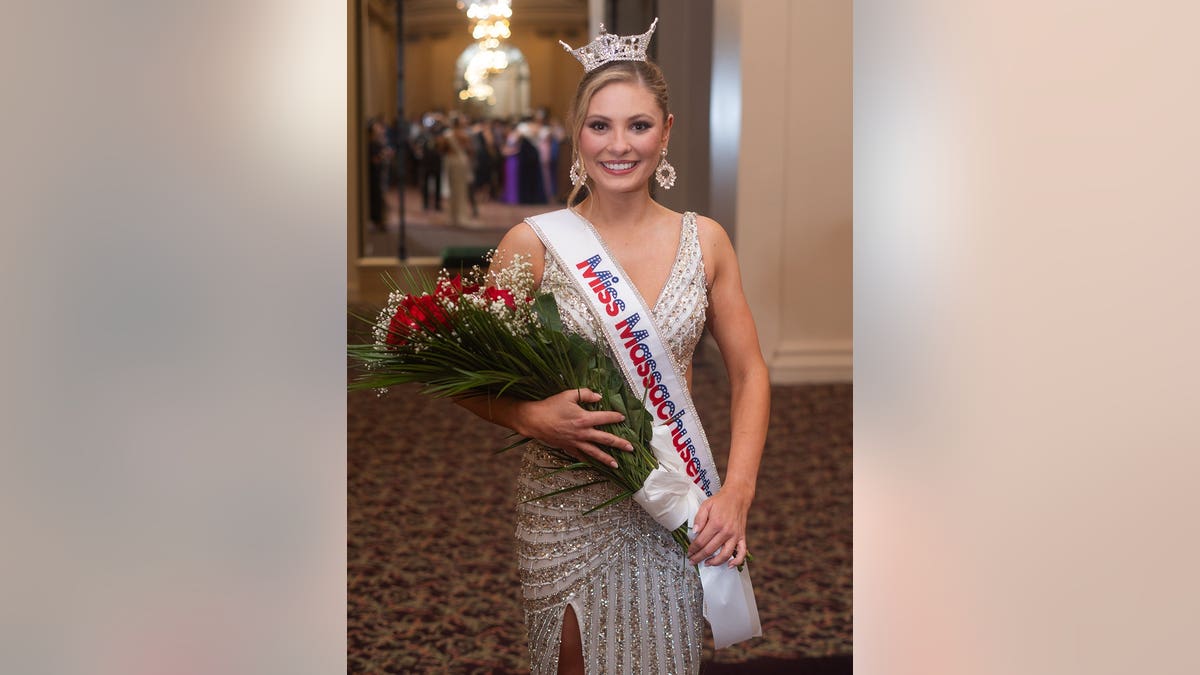 Ashlyn Mercier in a sparkling gown holding flowers wearing a sash and tiara.