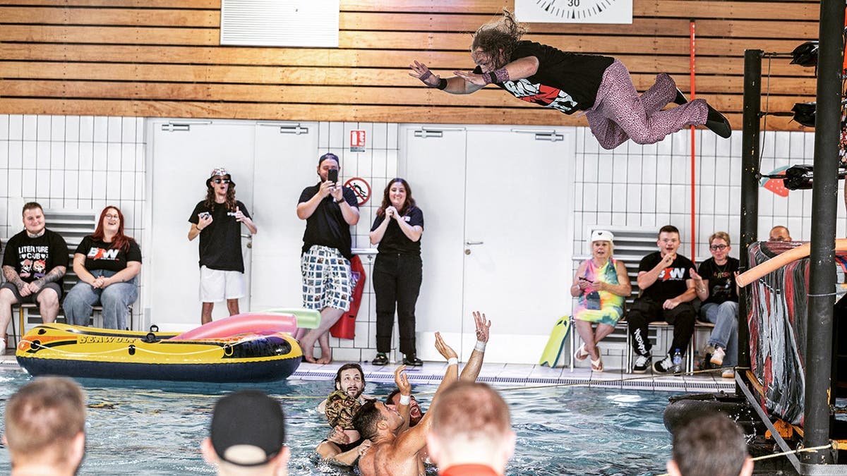 A wrestler dives into the pool