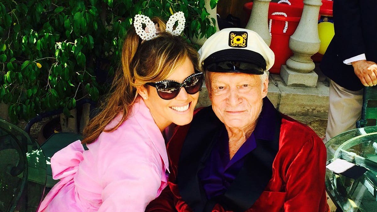 Sandra Taylor in a pink robe and bunny ears posing with Hugh Hefner.