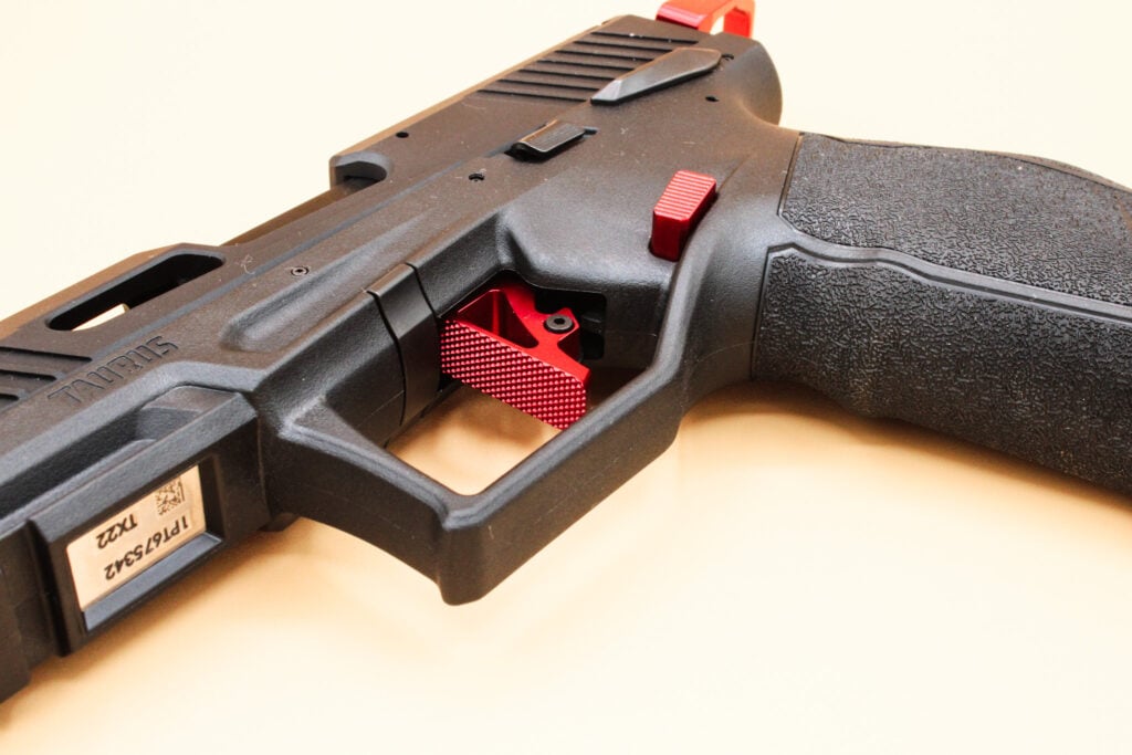 Handgun with black grip, red trigger, and visible serial number on slide.
