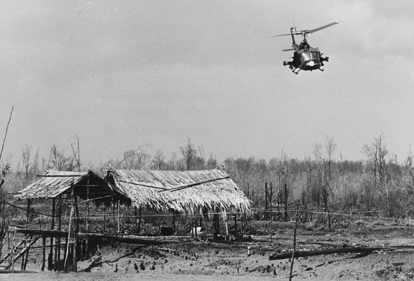 UH-1 Iroquois helicopter from Light Attack Squadron Three flies over an abandoned Viet Cong village on the Cualon River