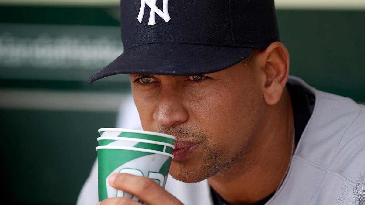 Alex Rodriguez sips water in the Yankees' dugout during a game.