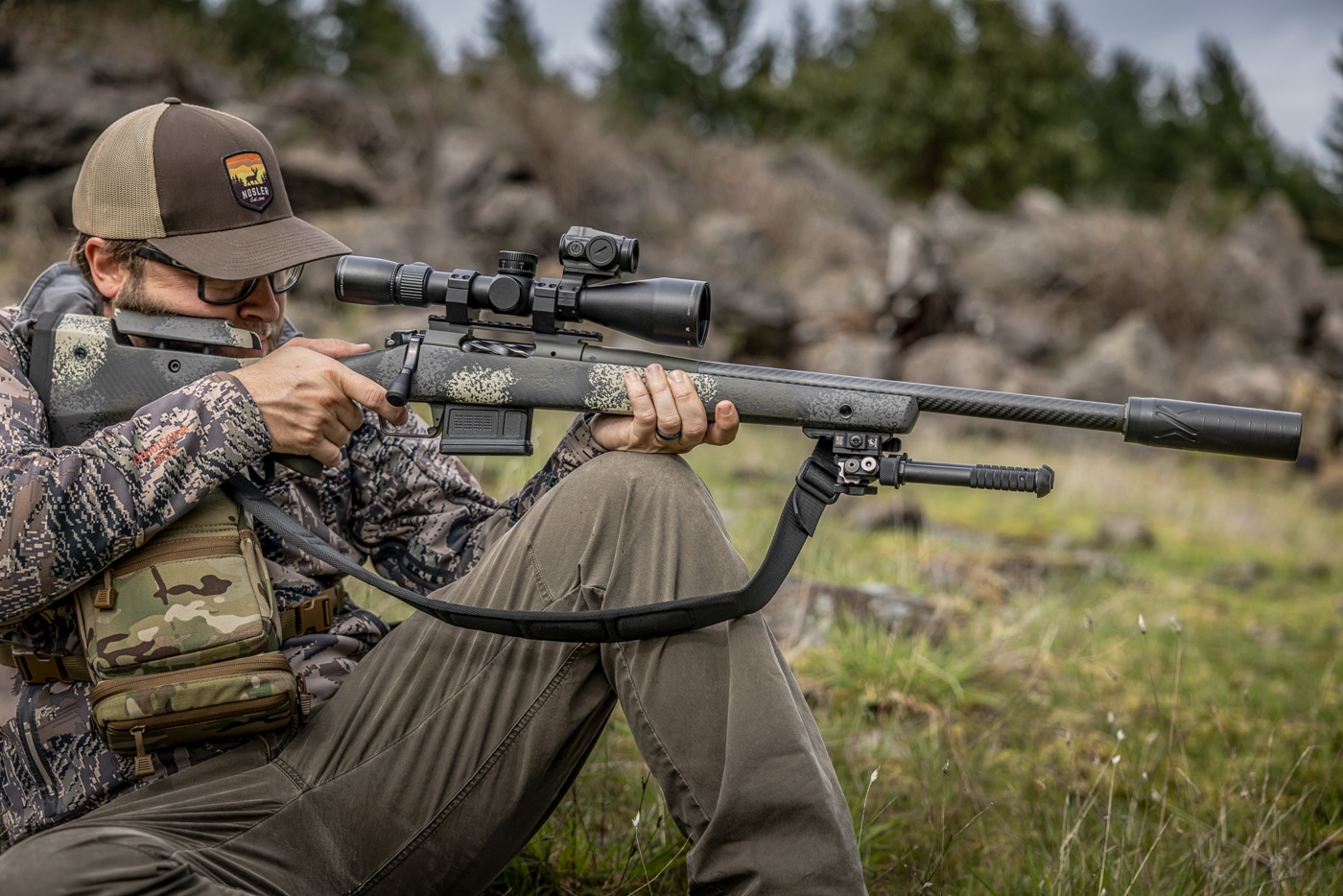 author shooting from seated position in the field having a red dot mounted at 12 o clock on the scope