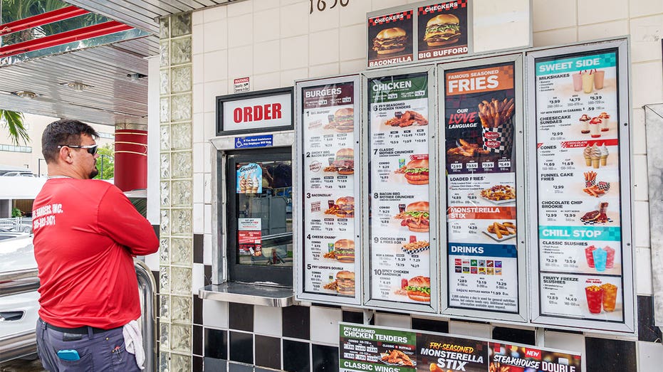 Customer reading the menu at a Checkers walk-up ordering window in Miami, Florida