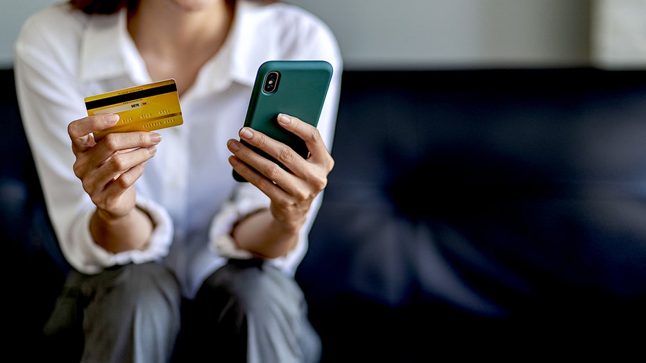 A person holding their credit card while on their phone