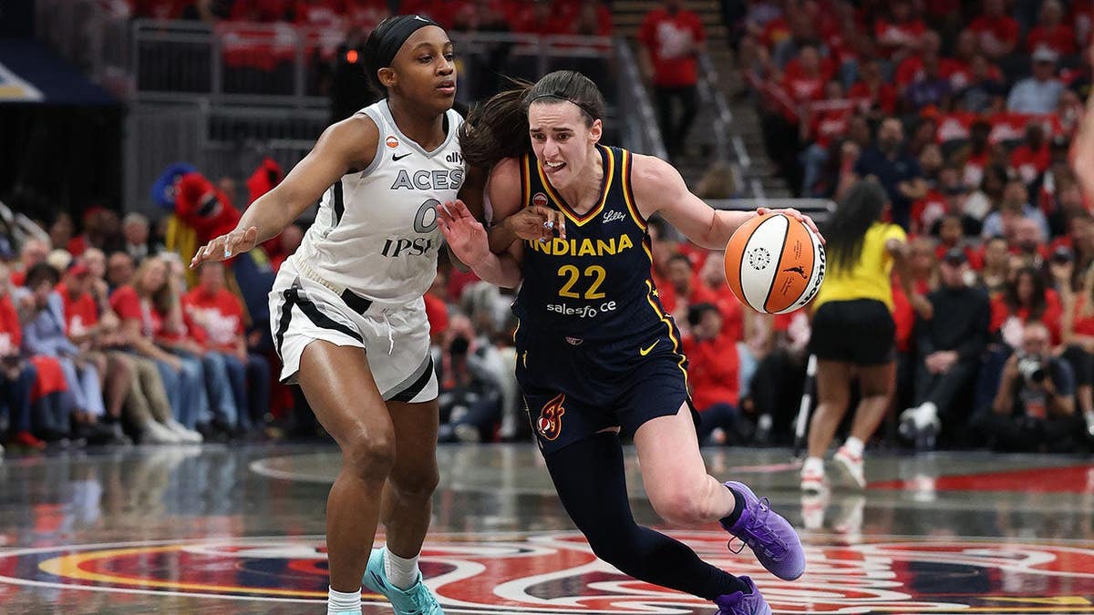 Caitlin Clark #22 dribbles while Jackie Young #0 defends during WNBA Playoffs game.
