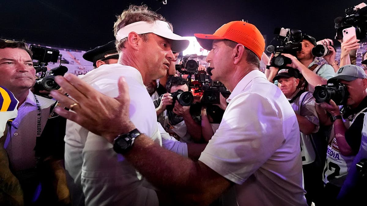 Lane Kiffin and Dabo Swinney greet each other after a college football game.