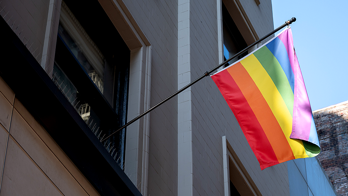 Rainbow flag hanging outside building.