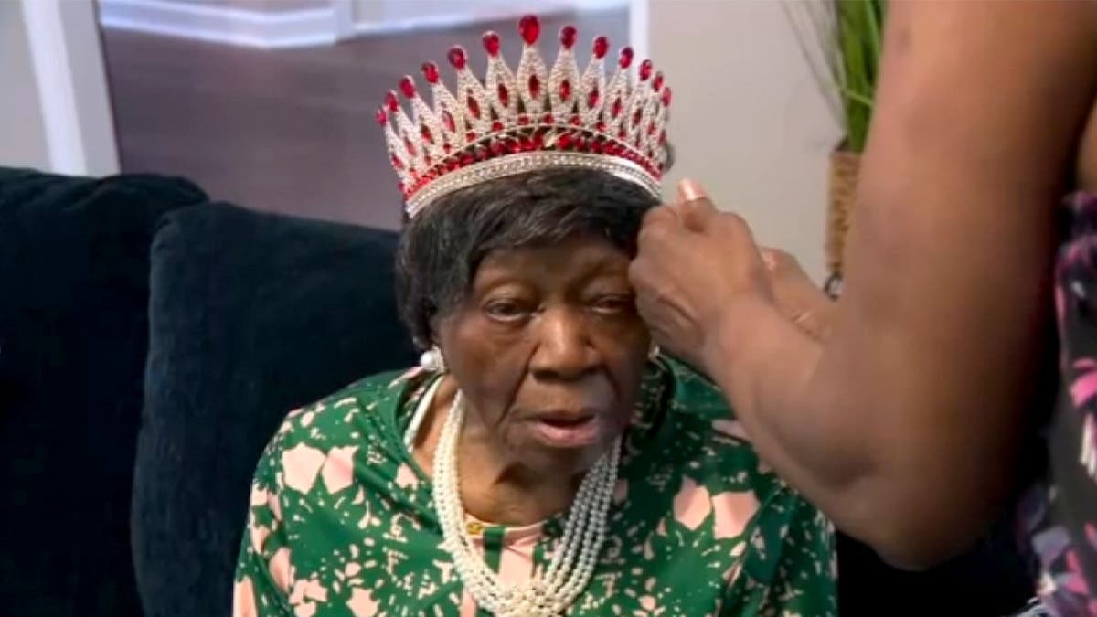 A relative puts a crown on Mabel Dunbar.