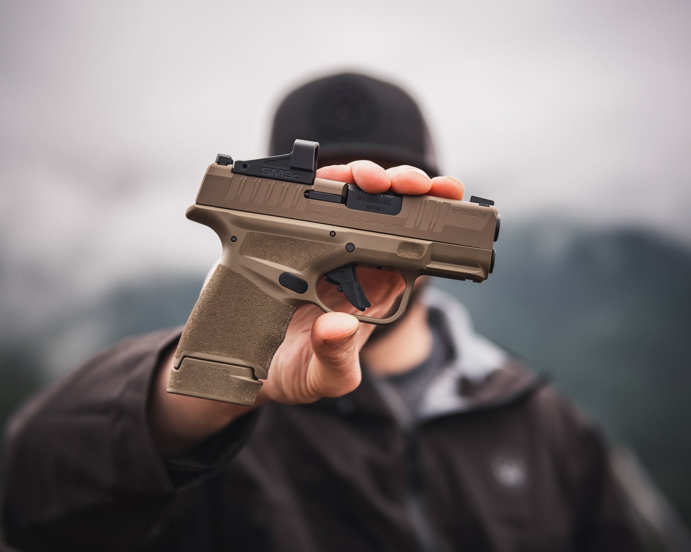 man holding Springfield Armory Hellcat out to show the red dot sight