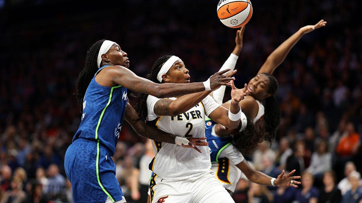 Myisha Hines-Allen of the Indiana Fever loses the ball driving against Natasha Howard of the Minnesota Lynx.