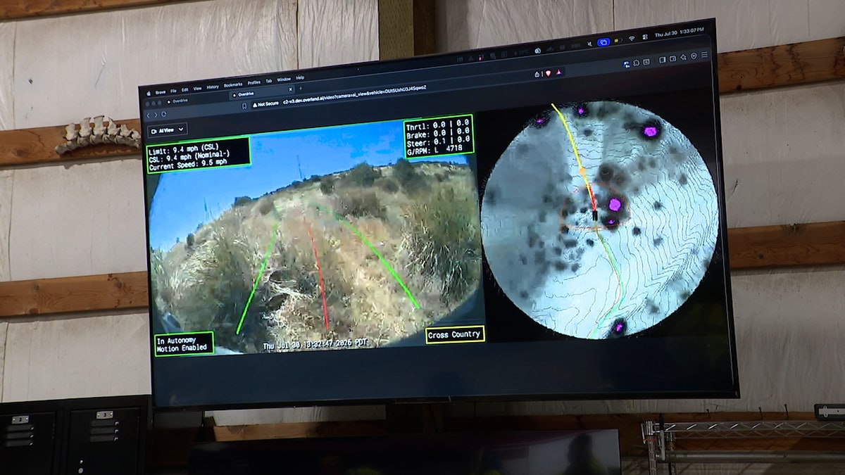 A monitor displays Overland AI’s autonomous driving system, showing a vehicle camera view alongside a terrain map and planned route.