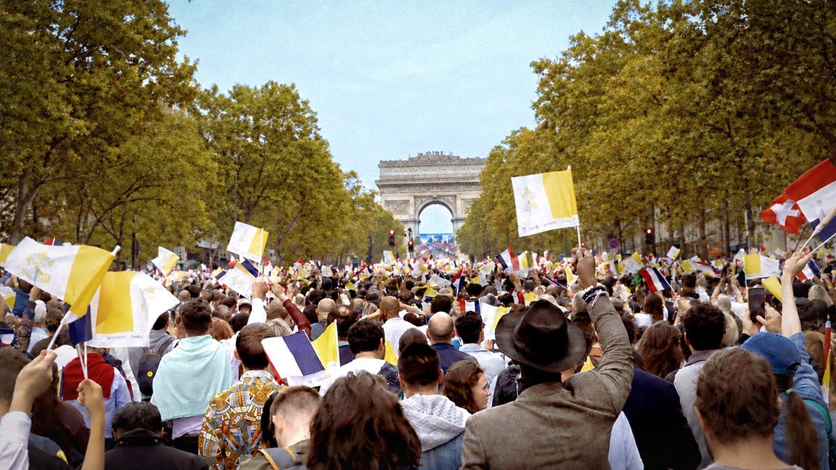 Crowd watches Pope Leo XIV on a giant screen near the Arc de Triomphe in Paris.