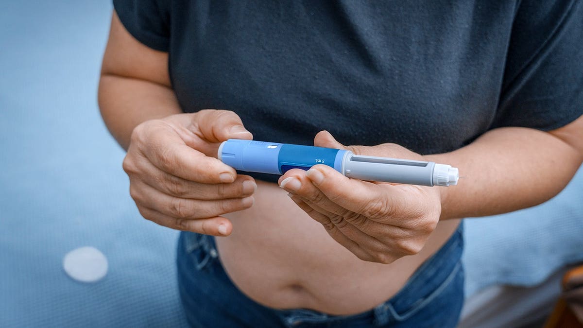 Woman holding an insulin pen prepares to administer diabetes treatment.