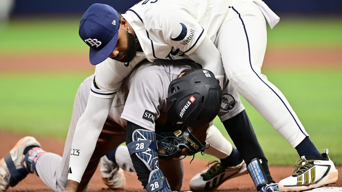 Junior Caminero tags out Austin Wells at third base during a baseball game.