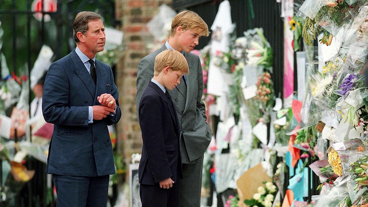 Prince William and Prince Harry examine floral tributes outside Kensington Palace.